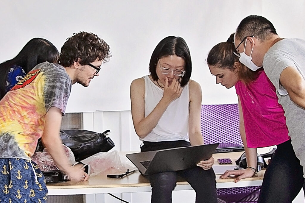 A group of toy design students looking at a laptop.